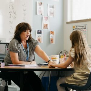 A Monument Academy teacher works one-on-one with an elementary student at a classroom table